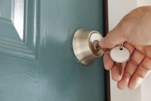 Man turning the key on the front door lock