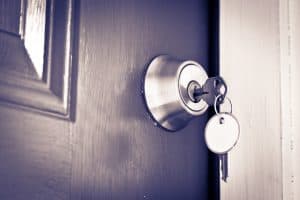 Keys hanging from a lock on a front door with copy space on the keyring tag